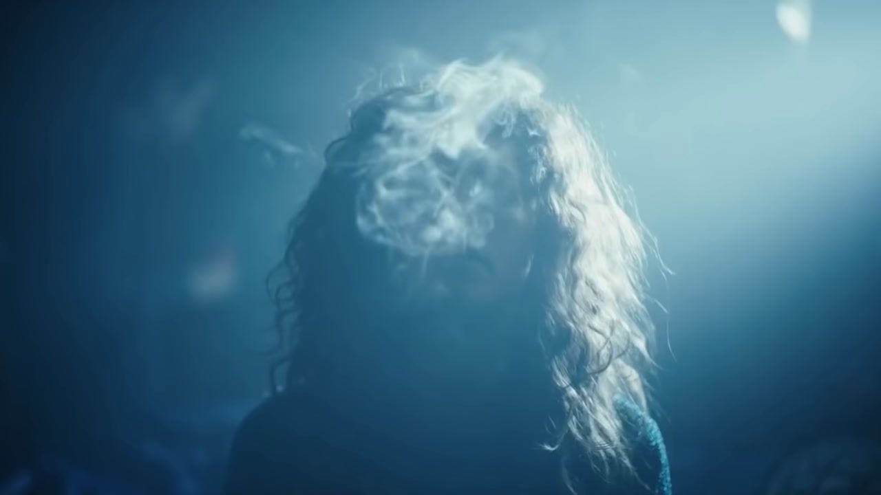 a woman with long hair standing in a dark room