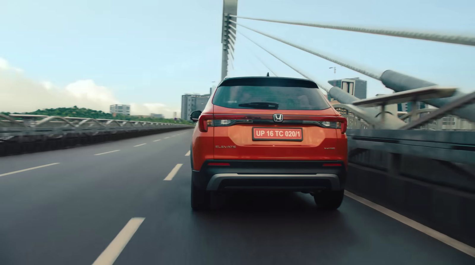 a red car driving on a bridge in the city