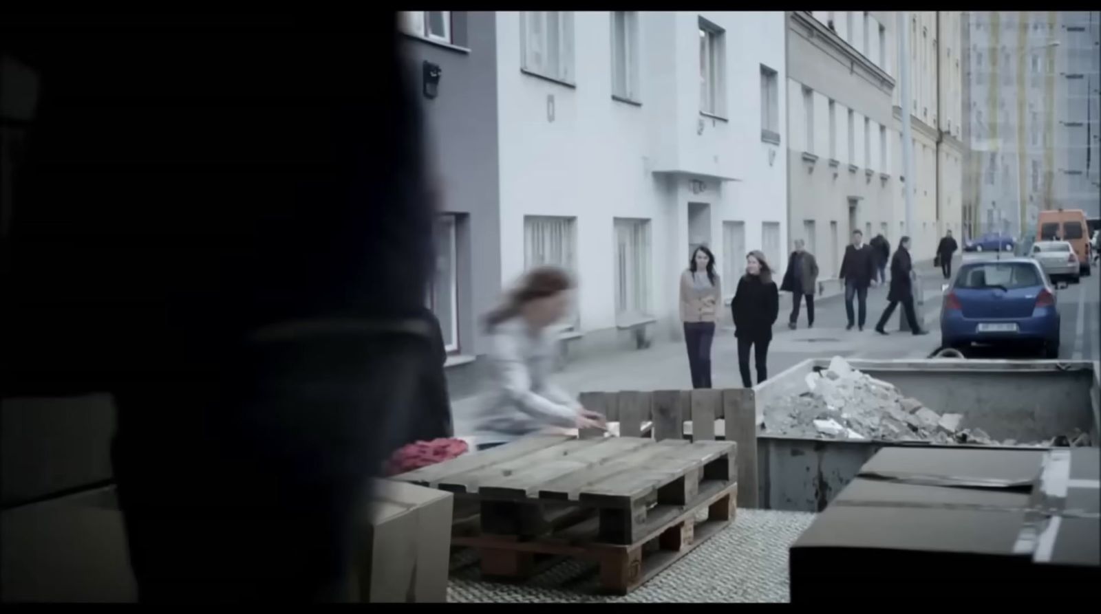 a group of people walking down a street next to tall buildings