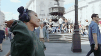 a woman wearing headphones walking down a street