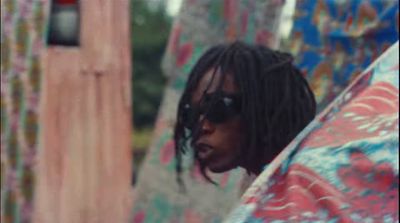 a man with dreadlocks holding a colorful umbrella