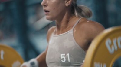 a woman holding a barbell in a gym