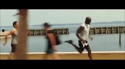 a group of men running on a beach next to the ocean