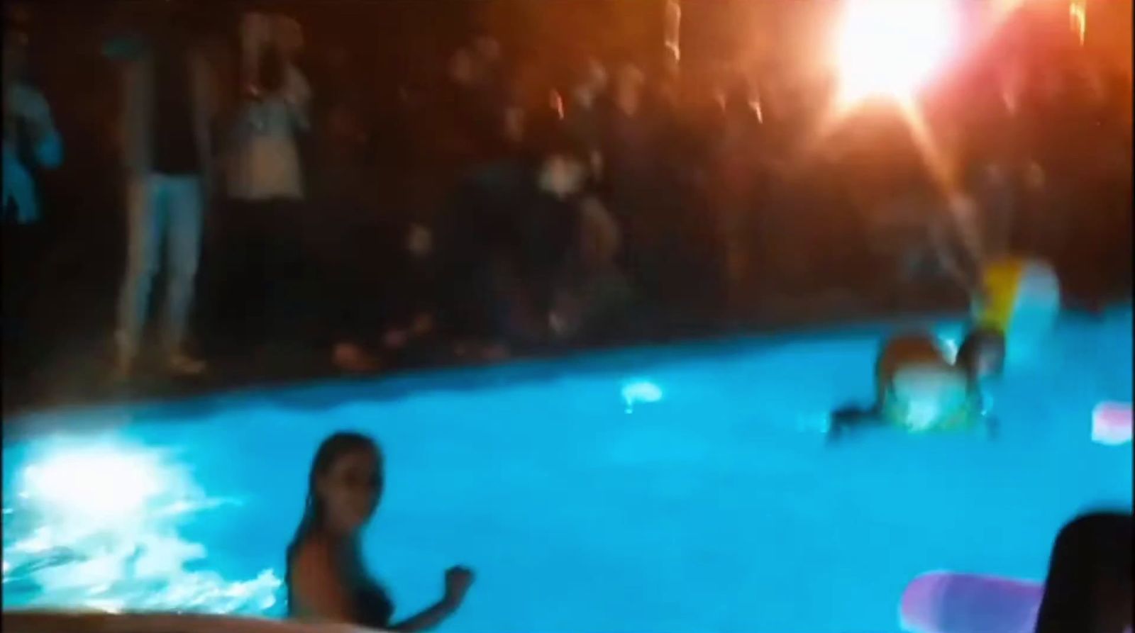 a group of people standing around a swimming pool