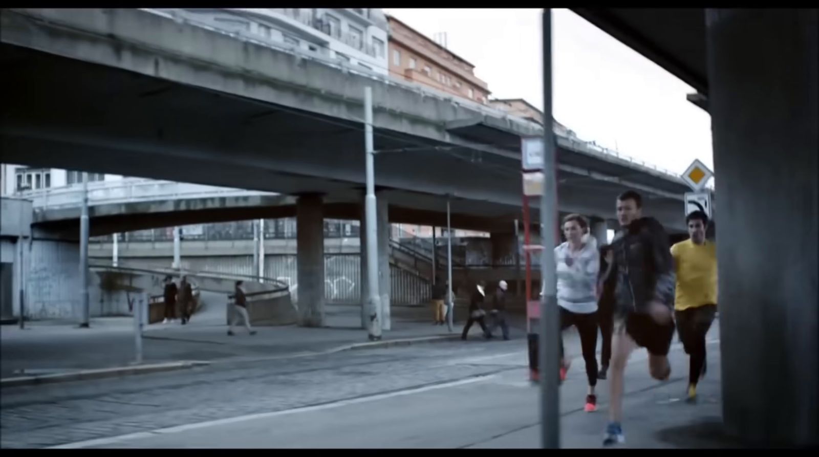 a group of people walking down a street next to a bridge