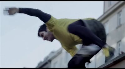 a man in a yellow shirt doing a trick on a skateboard