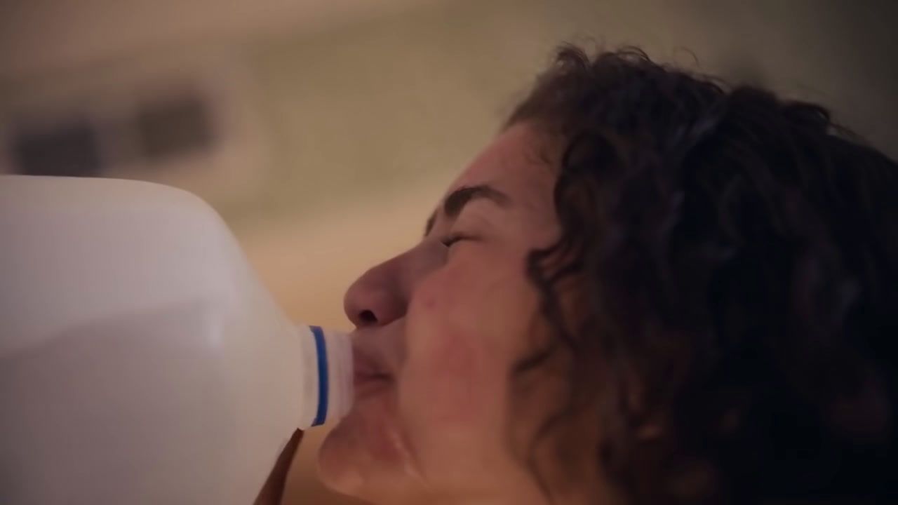 a woman drinking out of a white bottle