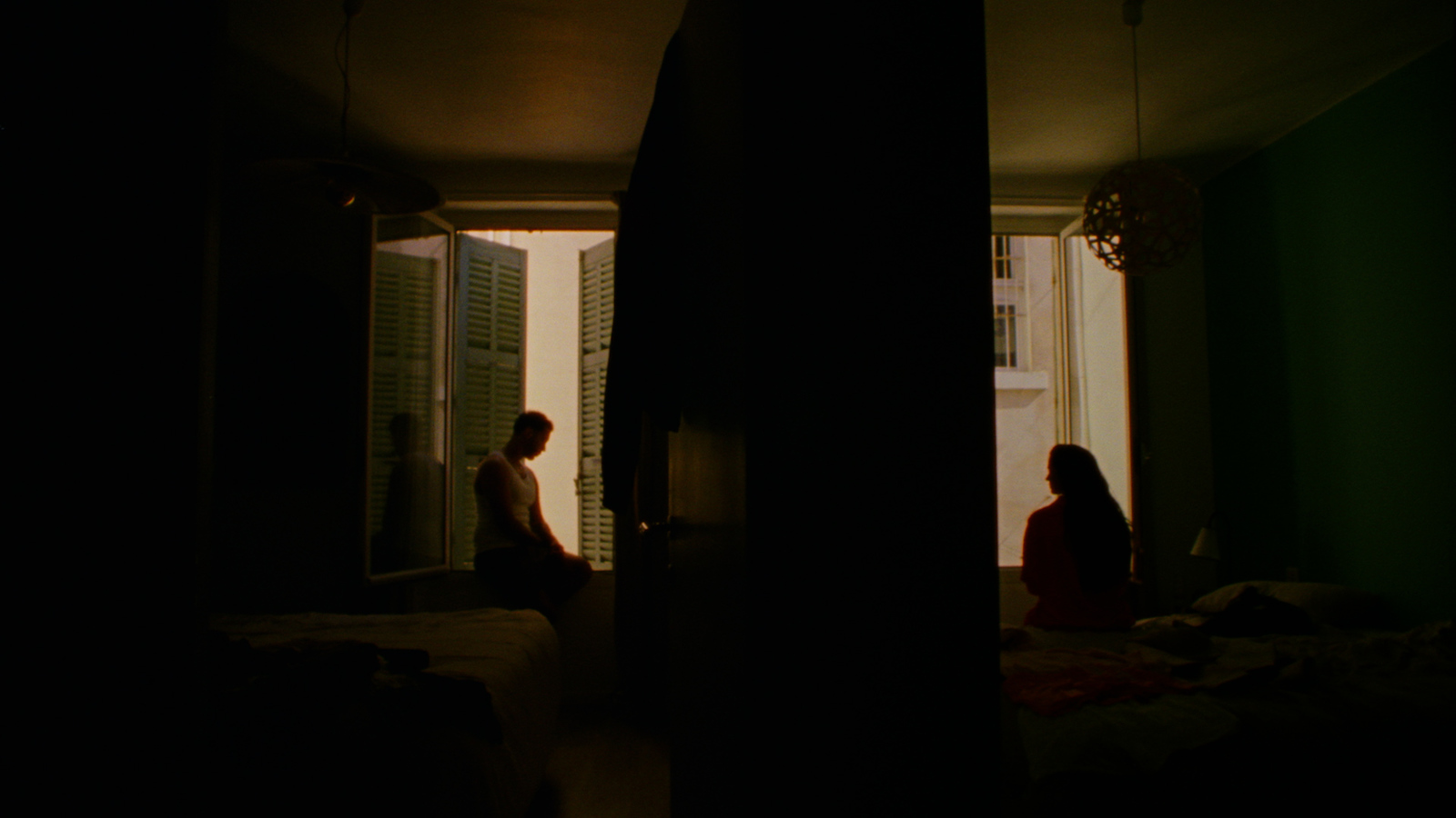 a man and a woman sitting on a bed in a dark room