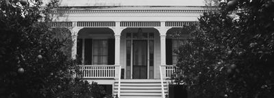 a white house with a porch surrounded by trees