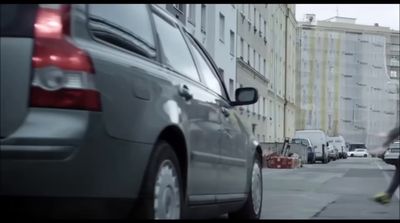 a man walking down a street next to parked cars