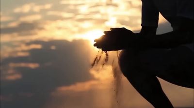 the silhouette of a person holding their hands in front of the sun