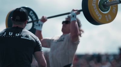 a man lifting a barbell in front of a crowd