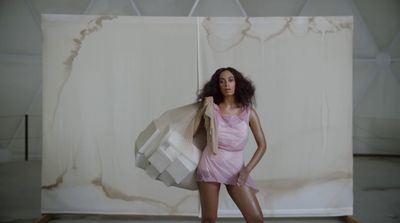 a woman in a pink dress holding a white bag