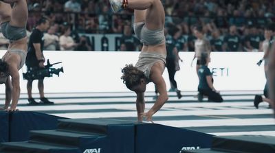 a woman doing a handstand on a beam in front of a crowd