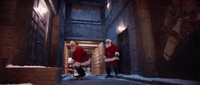 a couple of men in santa suits walking down a hallway