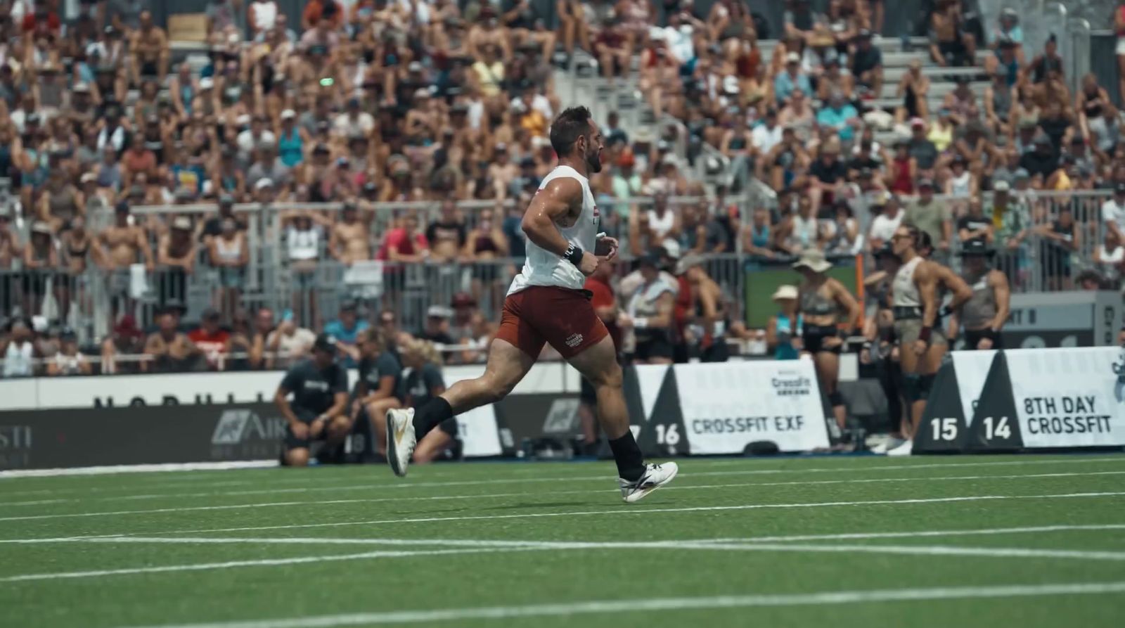 a man running on a field in front of a crowd