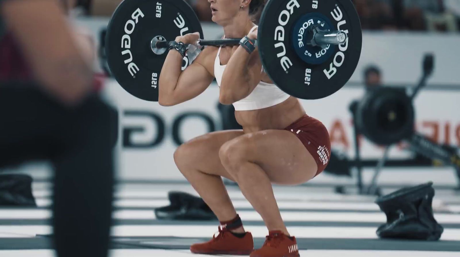 a woman squats with a barbell in her hands