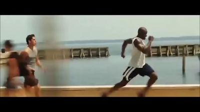 a group of men running on a pier next to the ocean