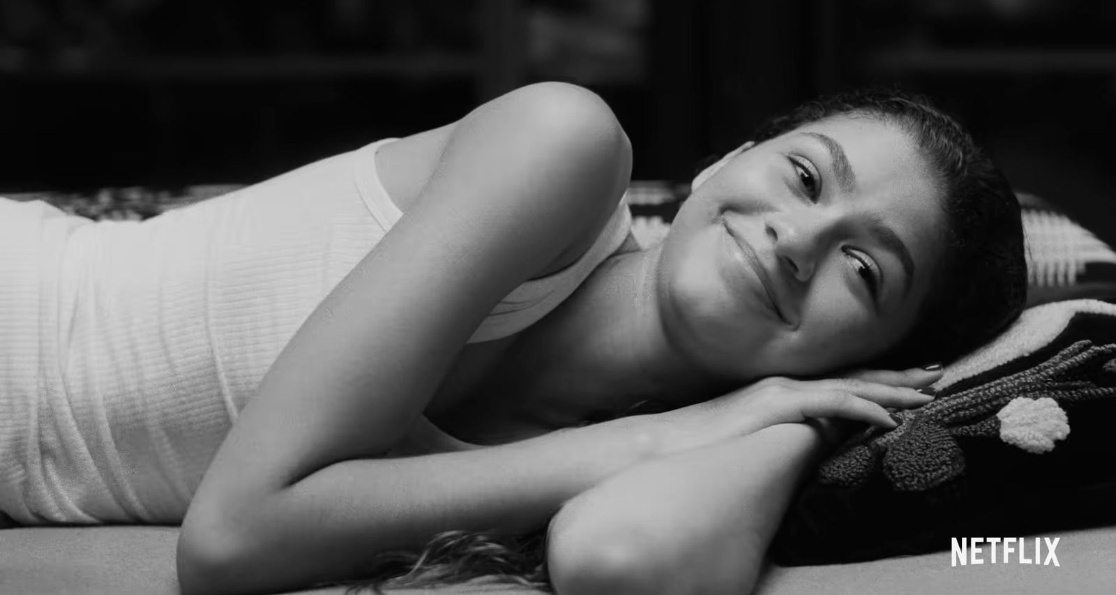 a woman laying on top of a bed next to a pillow