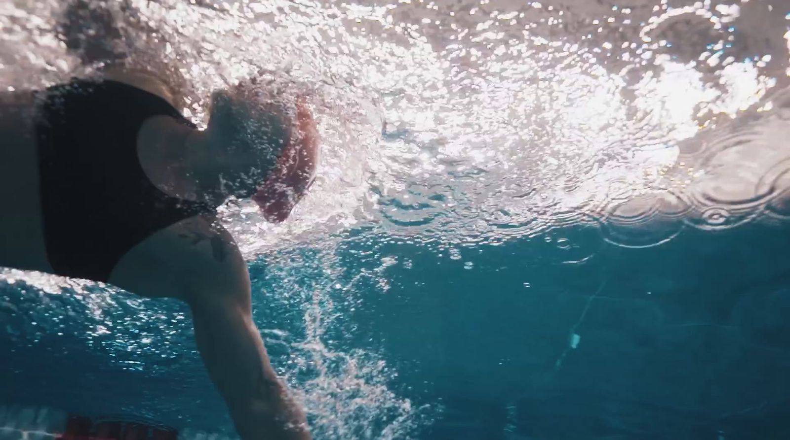 a woman in a black swimsuit swimming under water