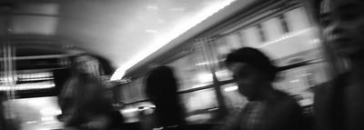 a black and white photo of people walking by a train