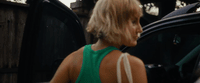 a woman in a green top getting out of a car