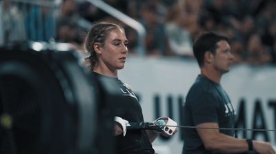 a woman holding a barbell in front of a man