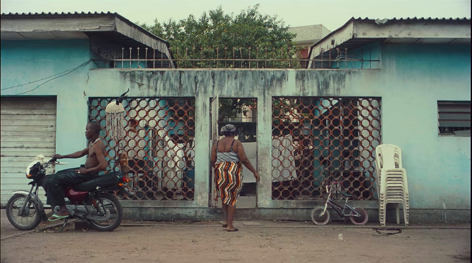 a man riding a motorcycle next to a blue building