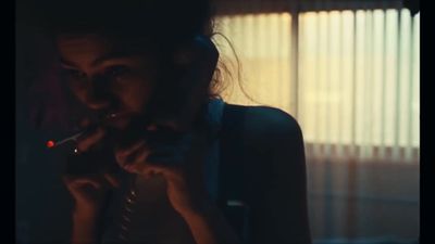 a woman smoking a cigarette in front of a window