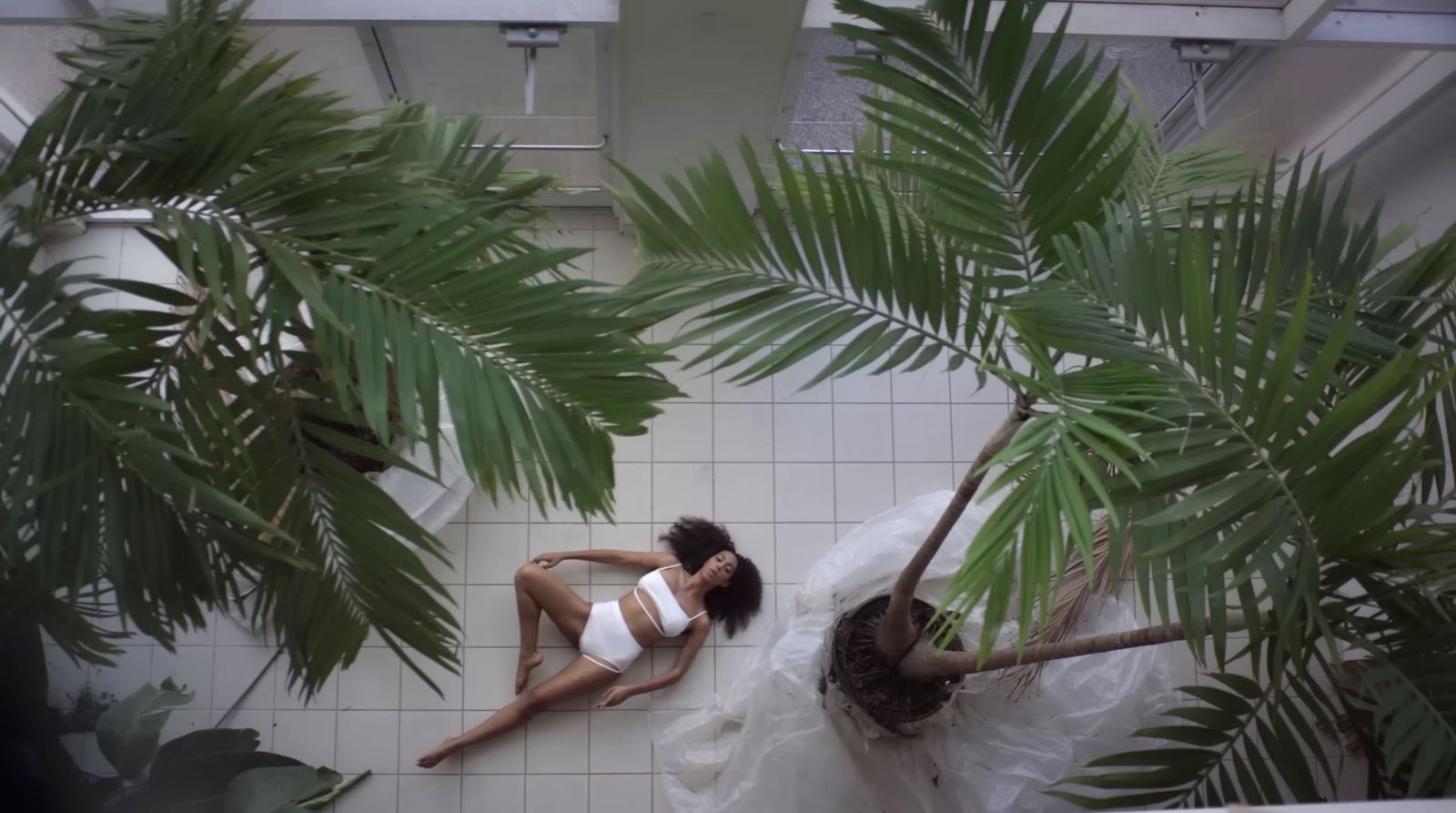 a woman in a white dress laying on a tiled floor