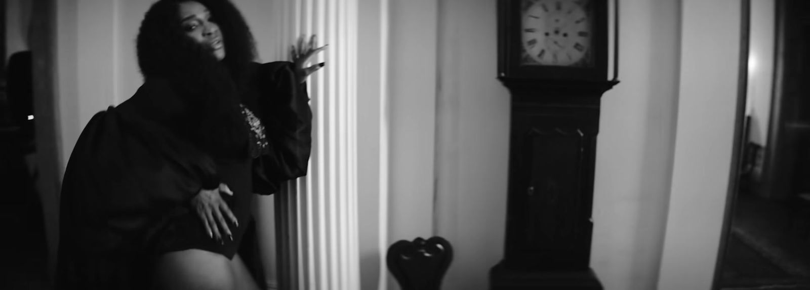 a woman leaning against a wall next to a clock