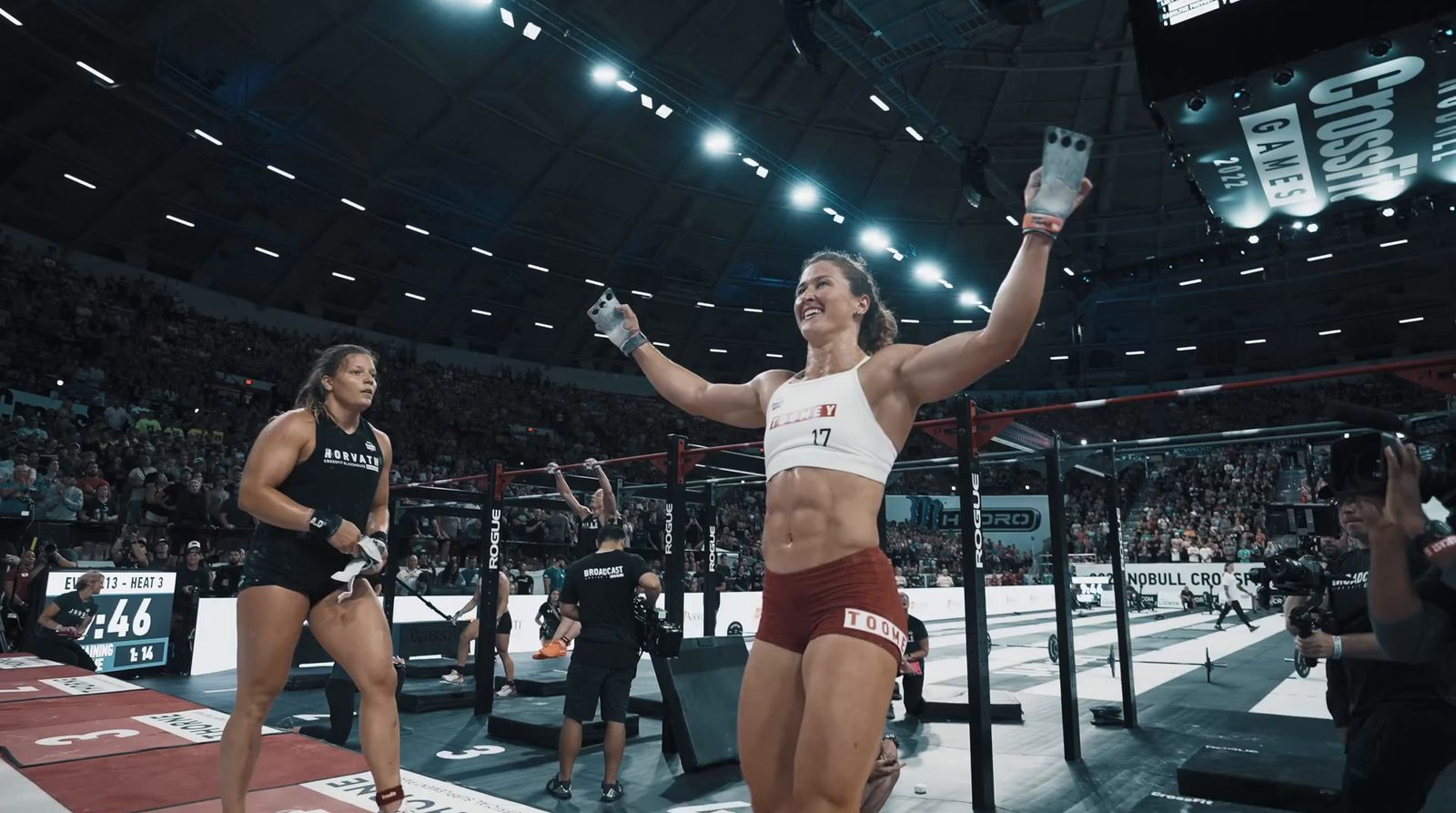 a woman in a white tank top and red shorts standing on a wrestling ring