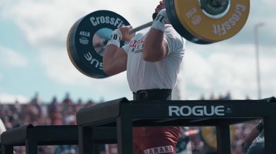 a man holding a barbell in front of a crowd