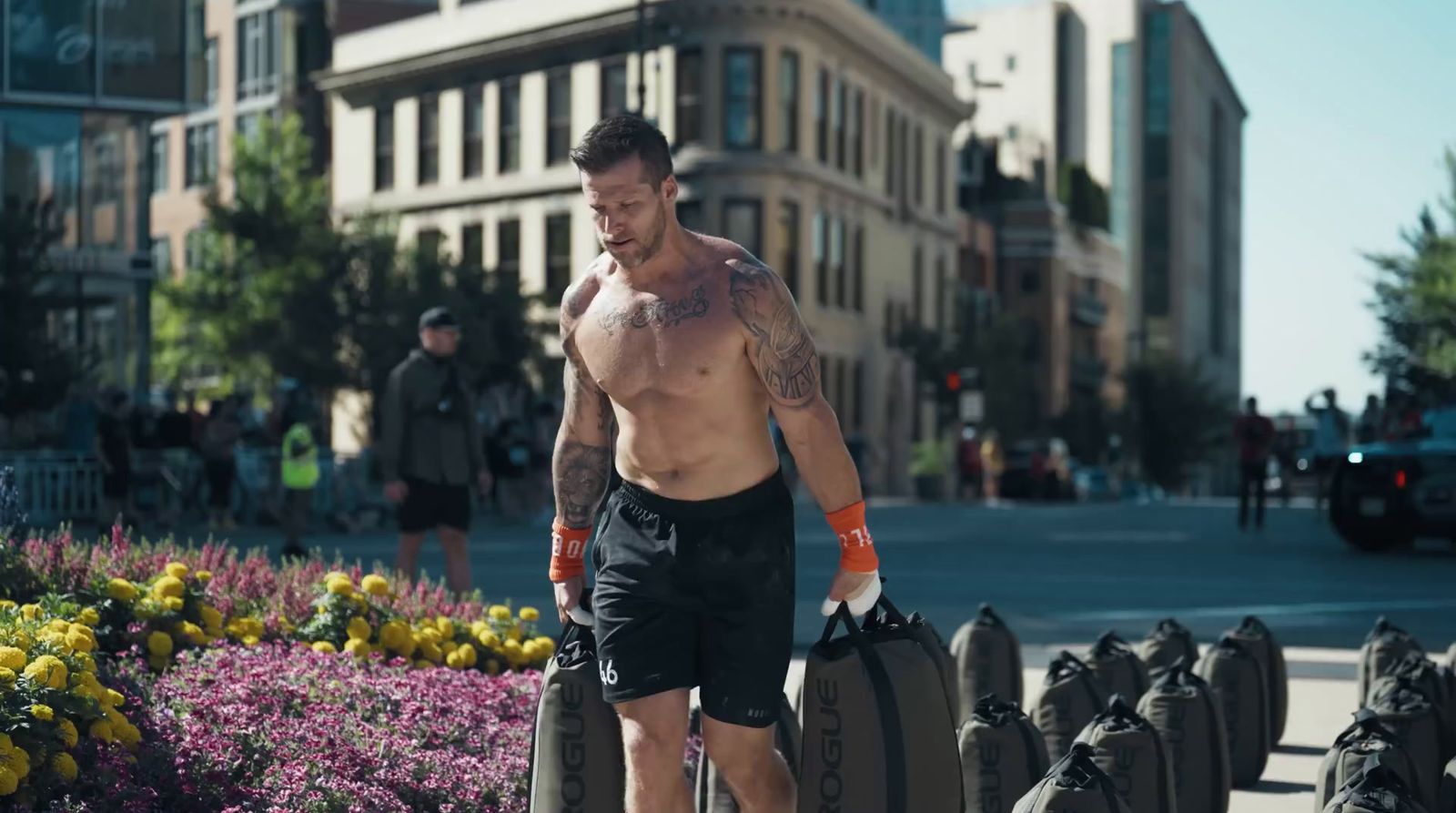 a shirtless man walking down a street with a suitcase