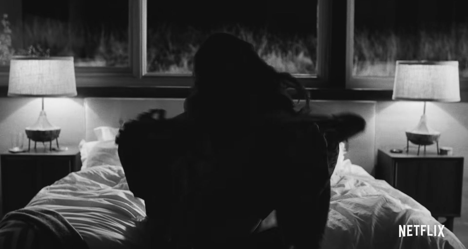 a woman sitting on a bed in a dark room