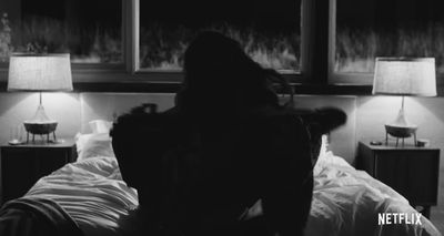 a woman sitting on a bed in a dark room