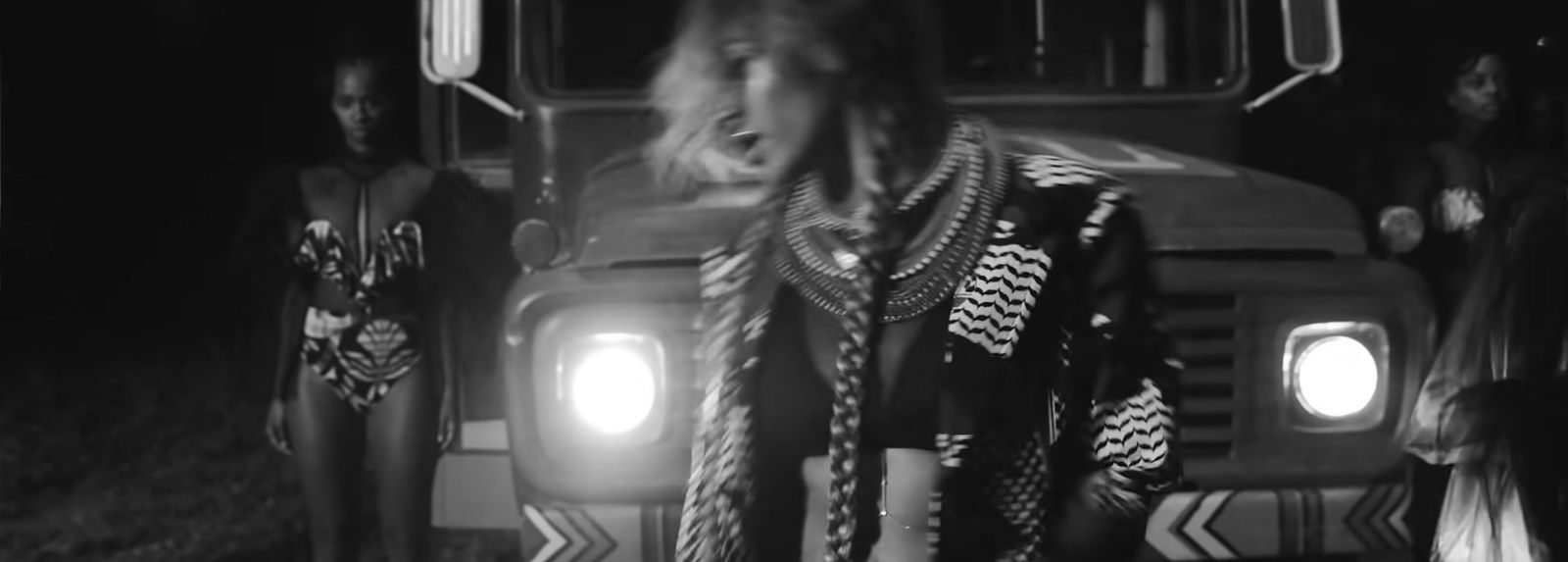 a black and white photo of a woman standing in front of a bus