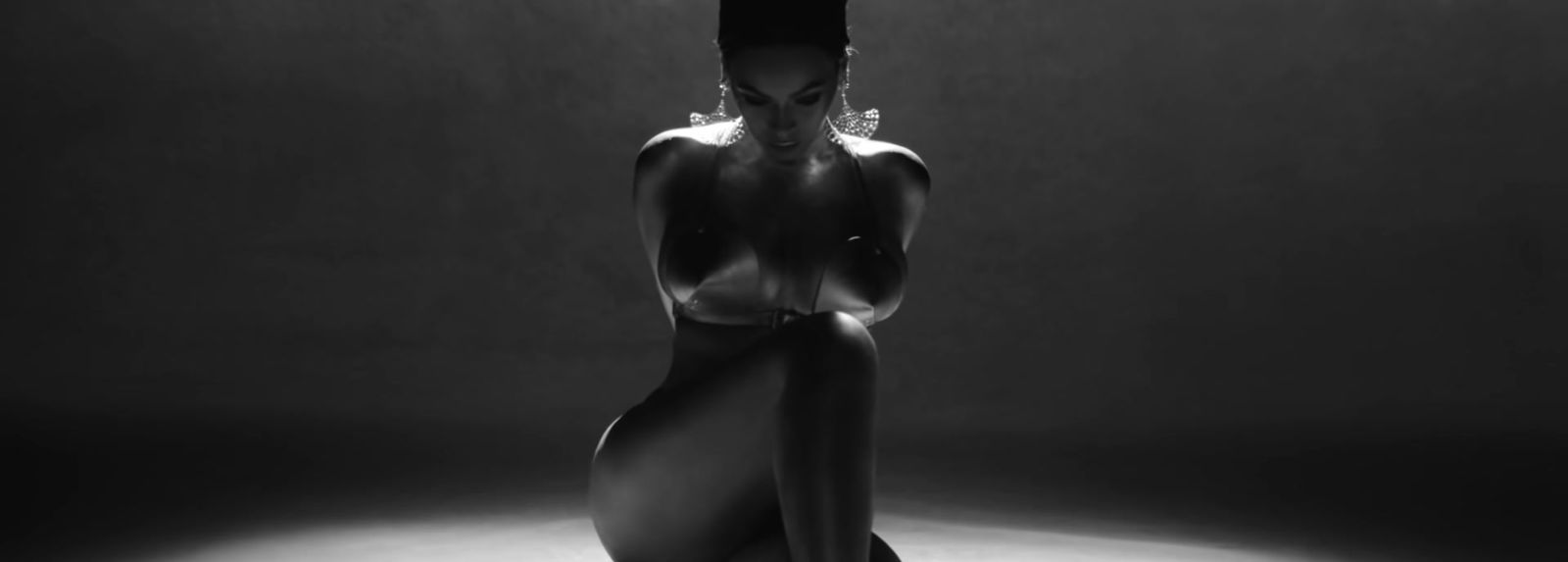 a naked woman sitting on a stool in a dark room