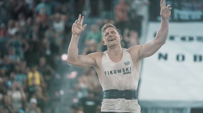 a man in a tank top raising his hands in the air