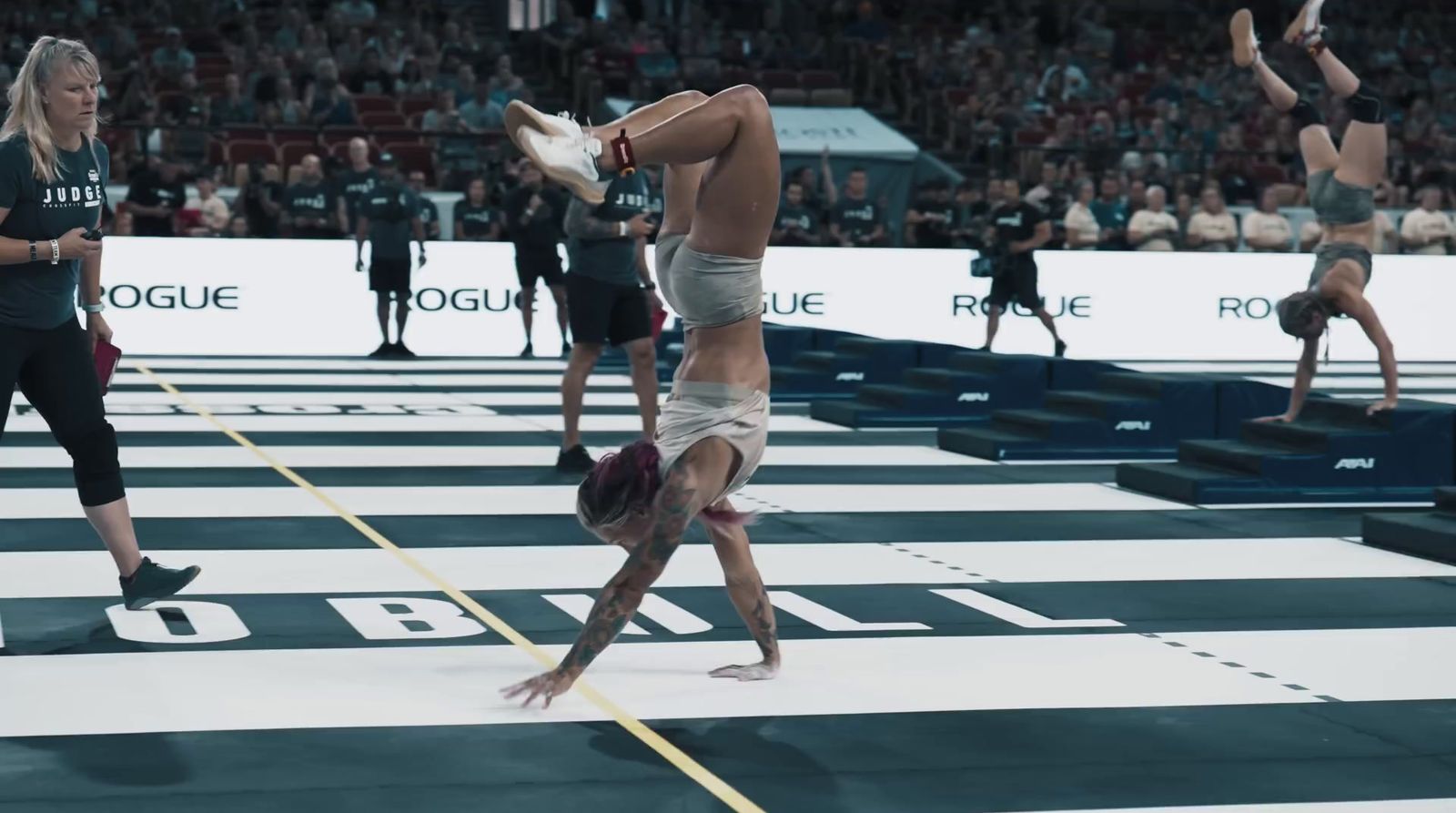 a woman doing a handstand on a floor in front of a crowd