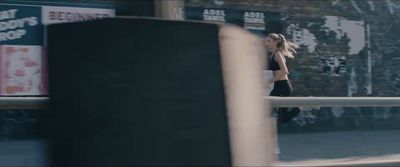 a woman walking down a street next to a fence