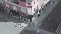 an aerial view of a pink building on a city street