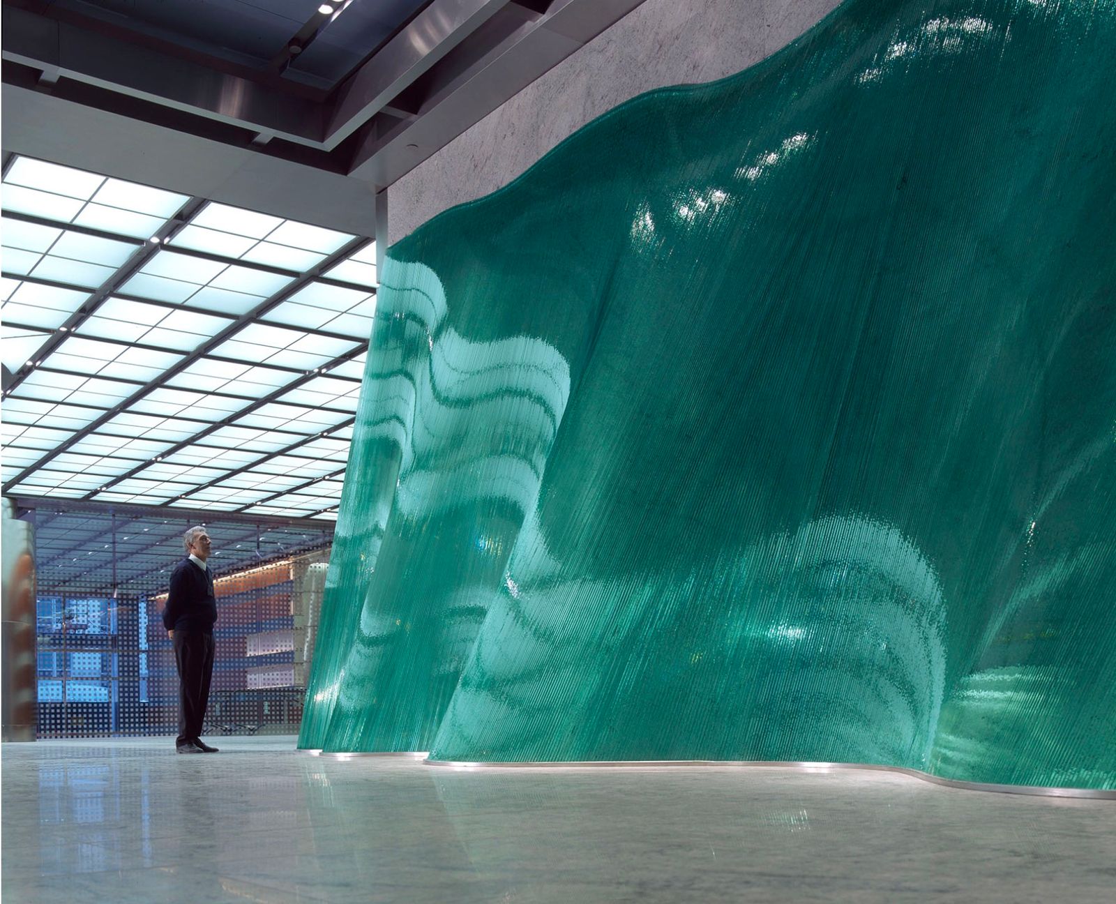 a man standing in front of a large green piece of art