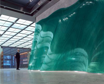 a man standing in front of a large green piece of art