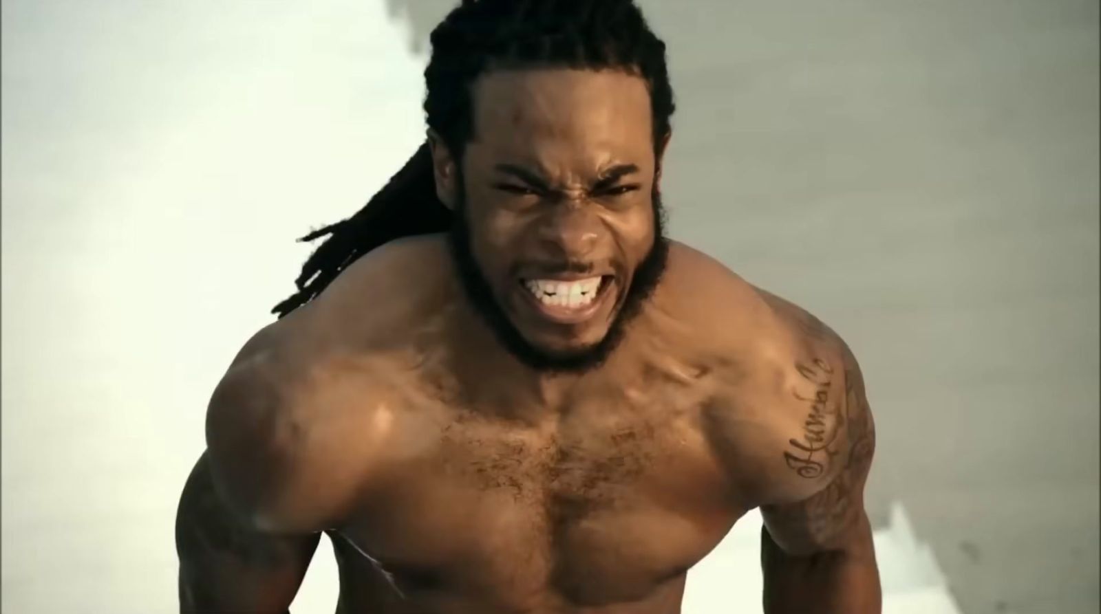 a shirtless man with dreadlocks on his head