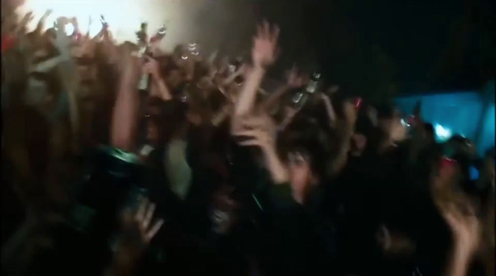 a crowd of people at a concert with their hands in the air