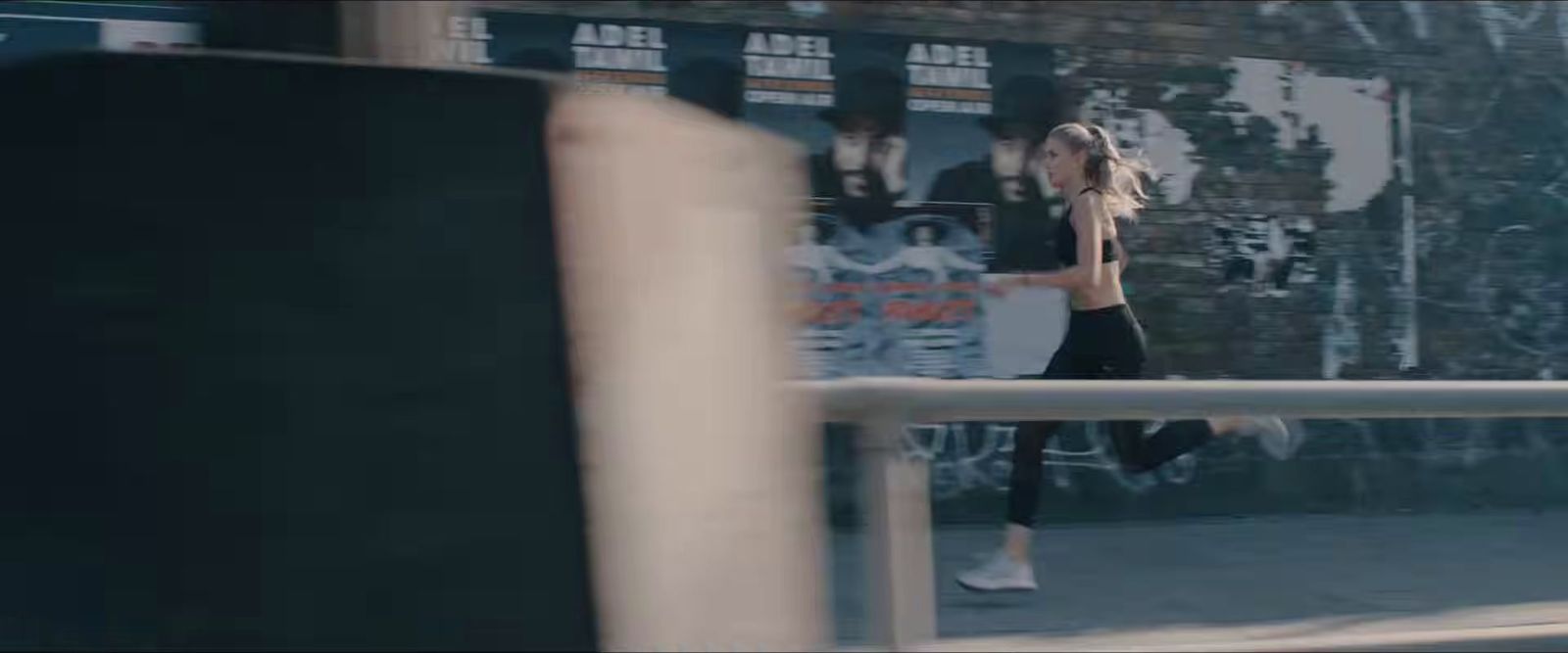 a woman is walking down a sidewalk near a wall