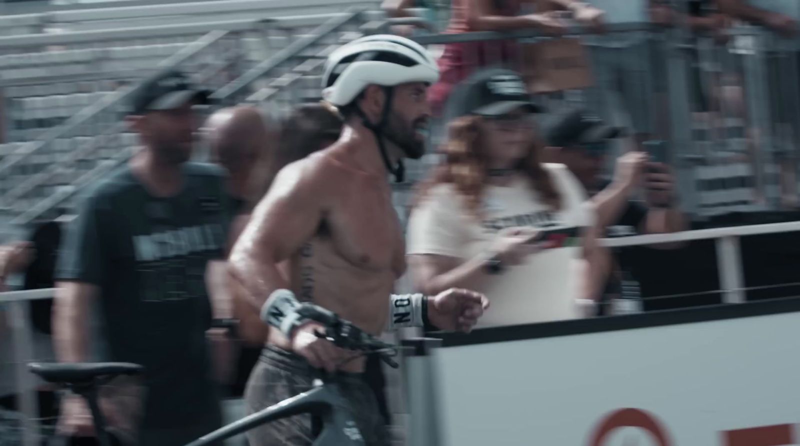 a man riding a bike down a street next to a crowd of people