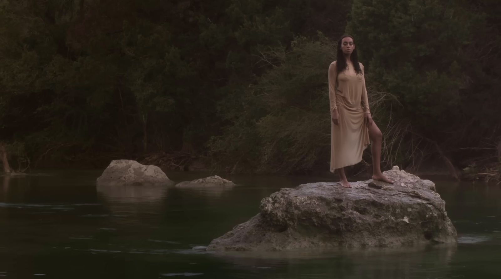 a woman standing on a rock in the middle of a river