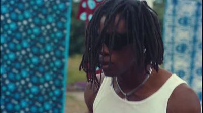 a man with dreadlocks standing in front of a wall